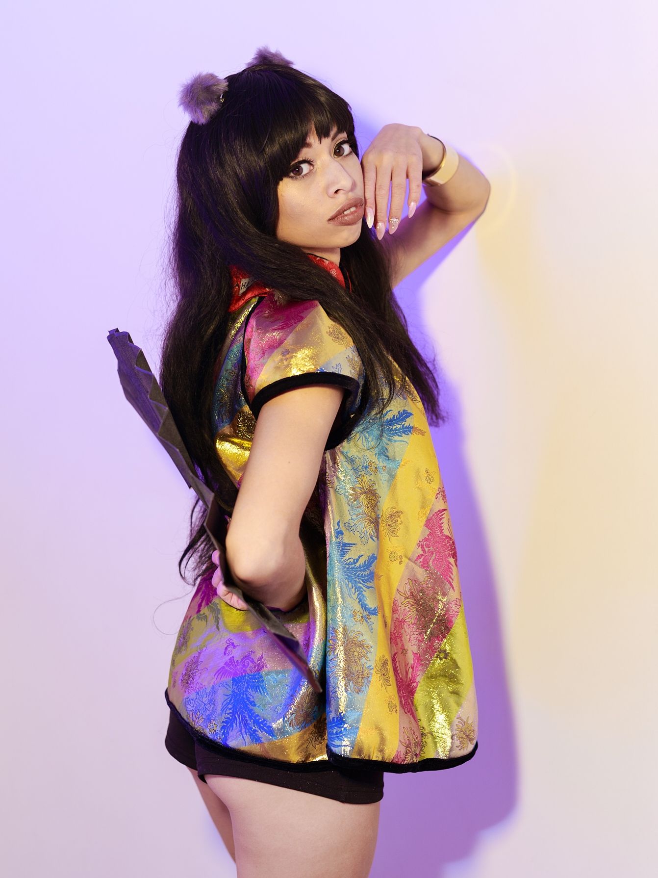 Fashion photography featuring colorful tie-dye clothing against purple background.