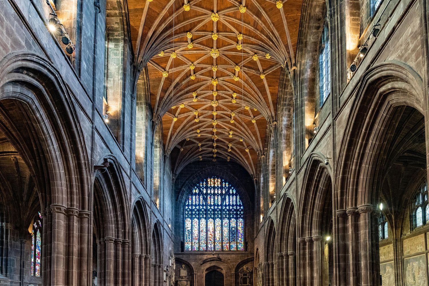 Gothic cathedral interior with ornate vaulted ceiling and stone arches in dramatic lighting.