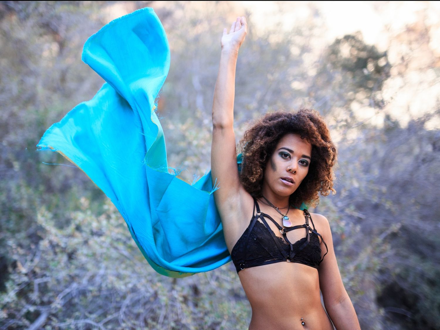 Dance performance with flowing blue fabric against natural backdrop.