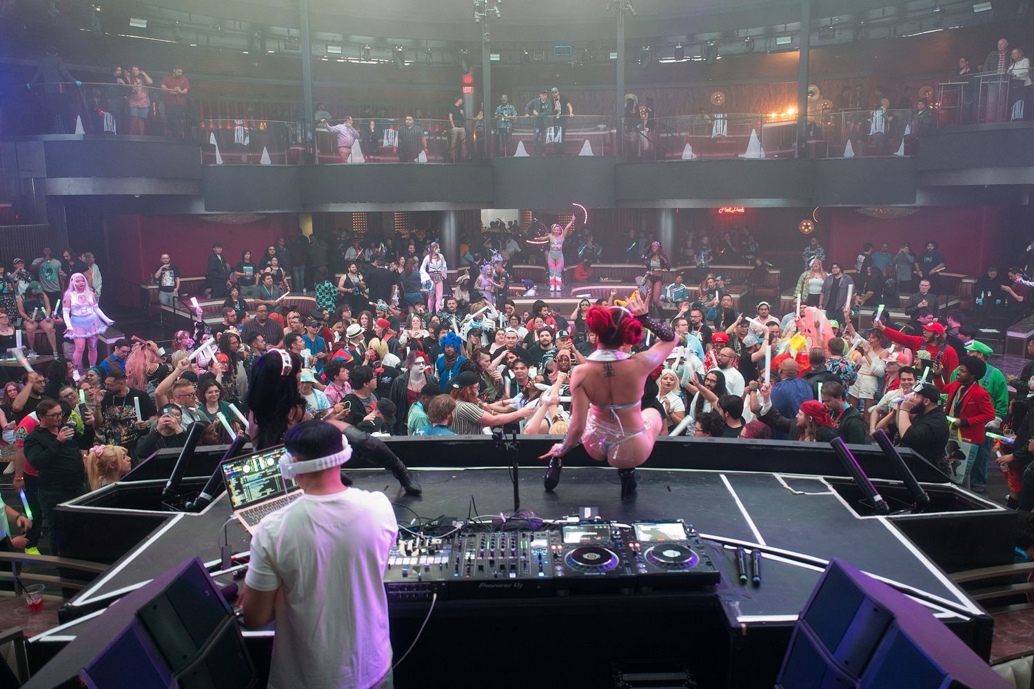 Large concert venue with crowd and stage lighting visible from DJ booth perspective.