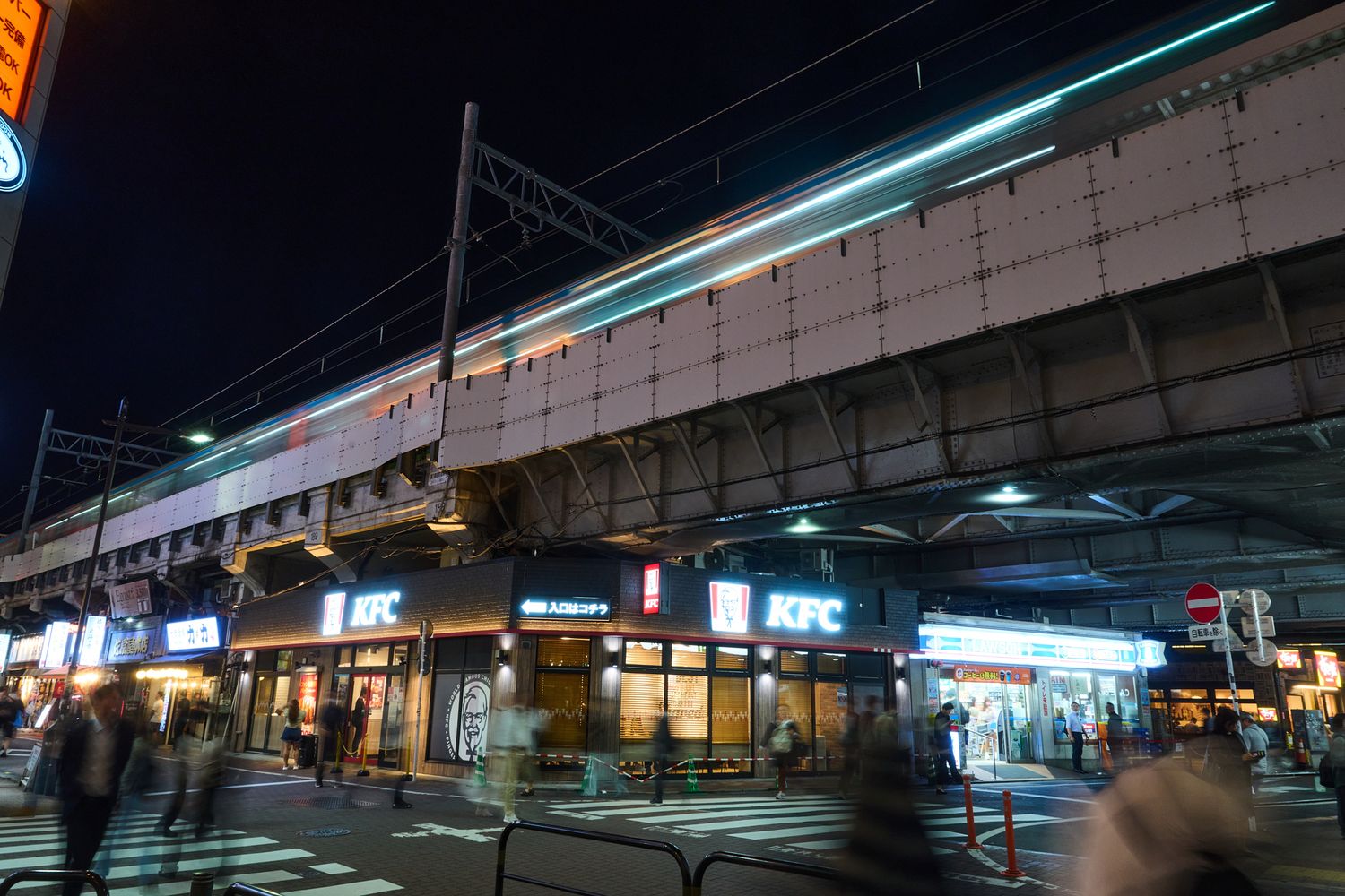Urban train station platform at night with fluorescent lighting and empty platform.