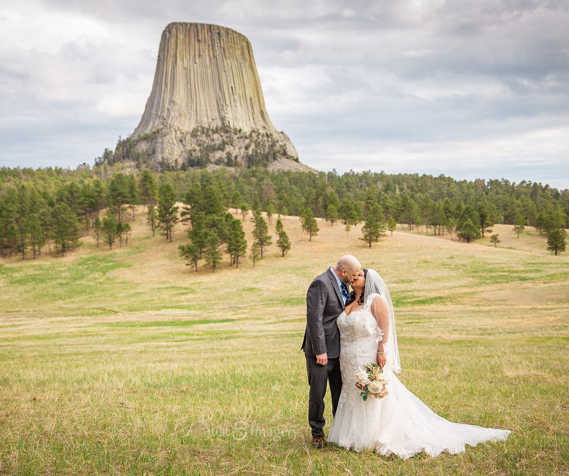 bride and groom kissing in front of Devils Tower