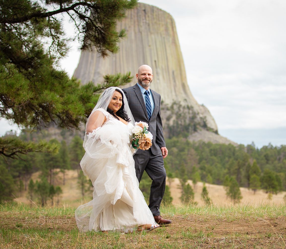 bride and groom walk arm in arm after wedding ceremony with Devils Tower in the background