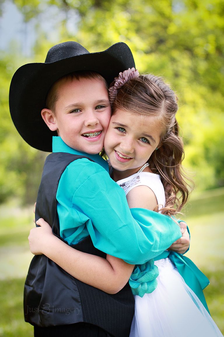 young ring bearer and flower girl hugging each other while looking at the camera