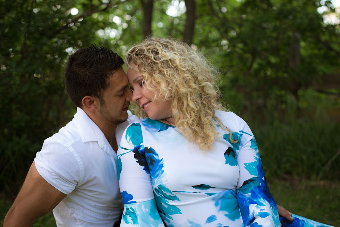 engaged couple look lovingly at each other in a green park
