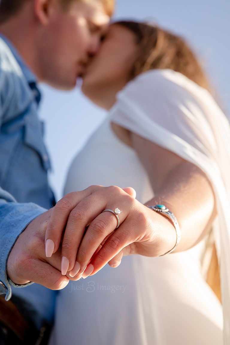 engaged couple kissing each other with the bride's ring in focus