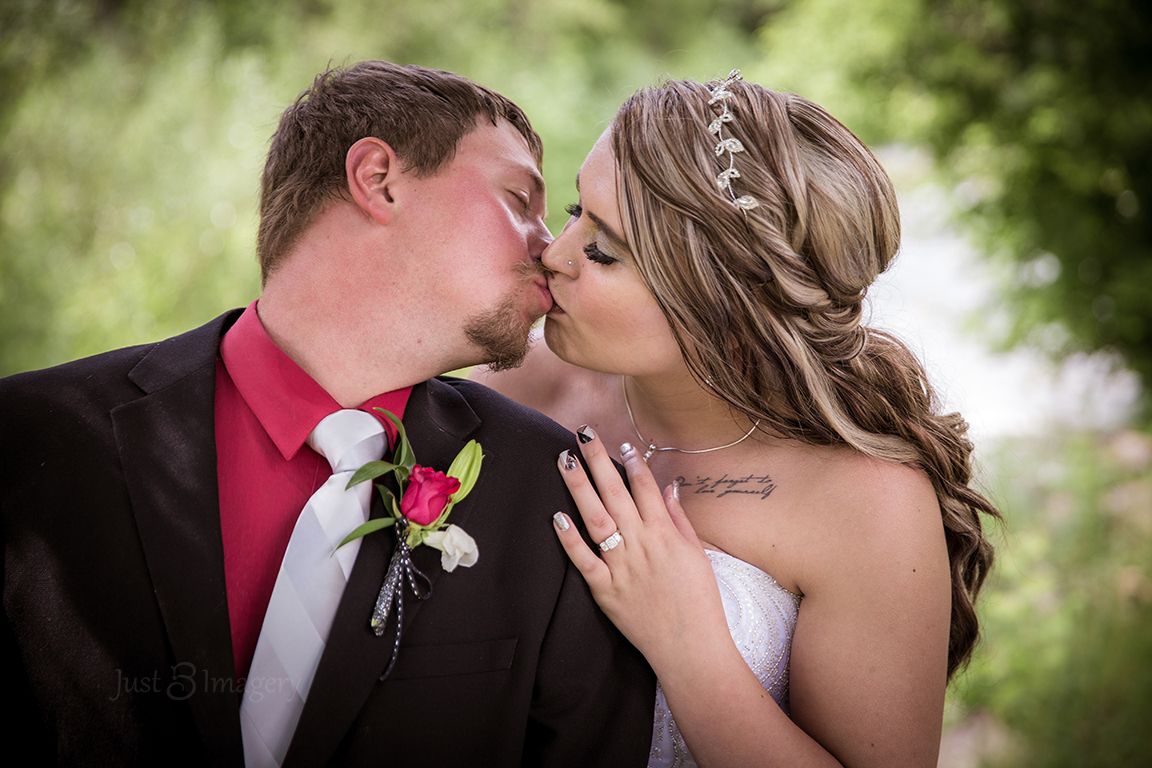 groom stretching back to kiss the bride, tattoos, rings, red roses