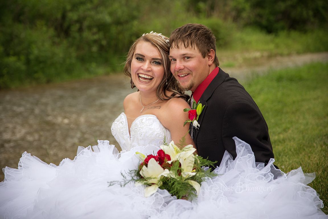 wedding couple sitting next to creek, green park