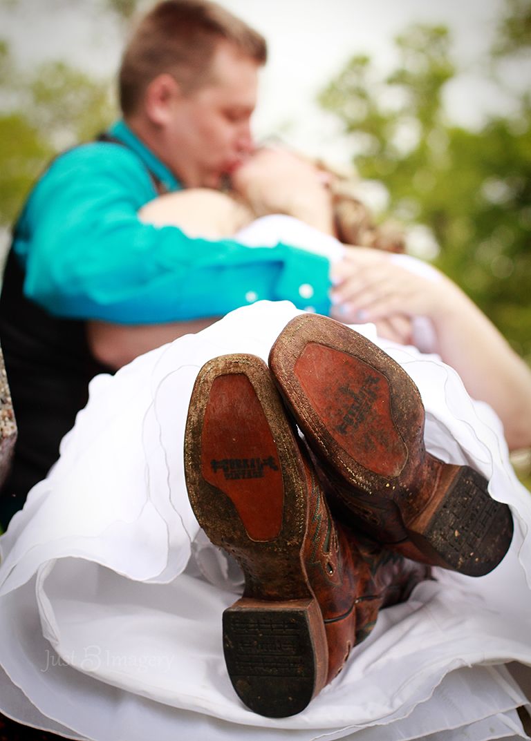 wedding couple sitting on a bench kissing each other with focus on the bottom of bride's boots