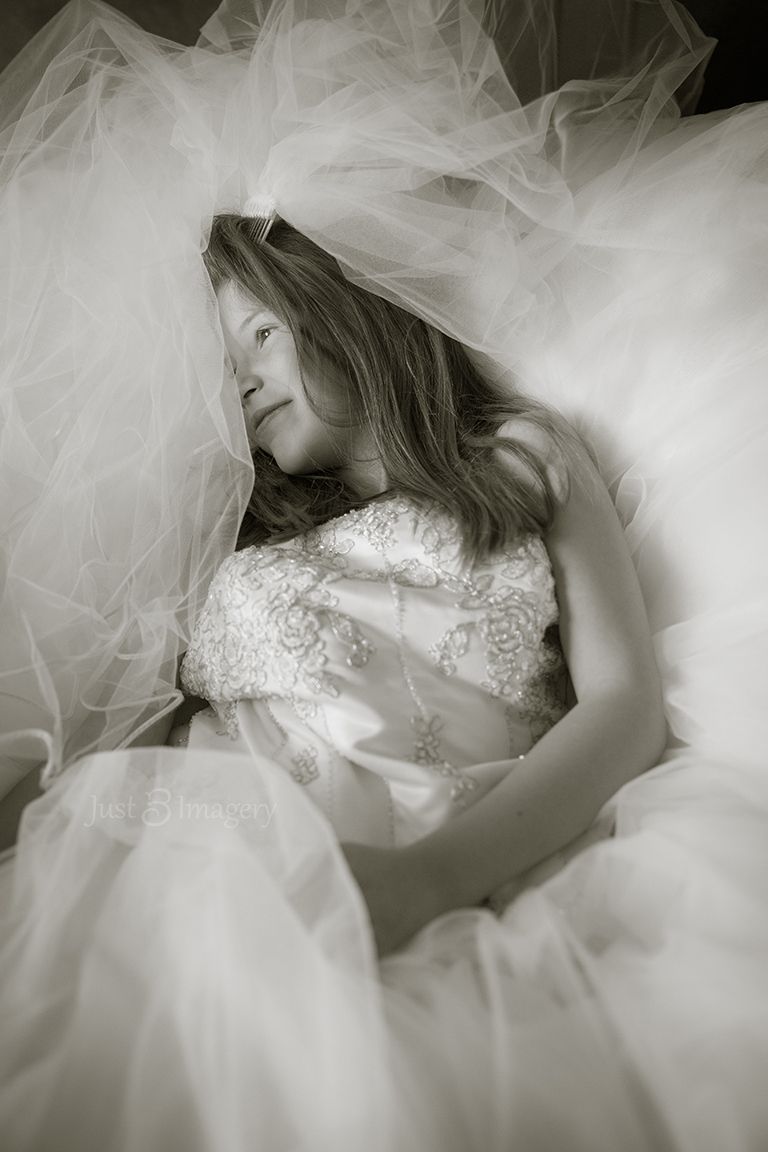 young girl in her mom's wedding dress, laying down, black and white portrait