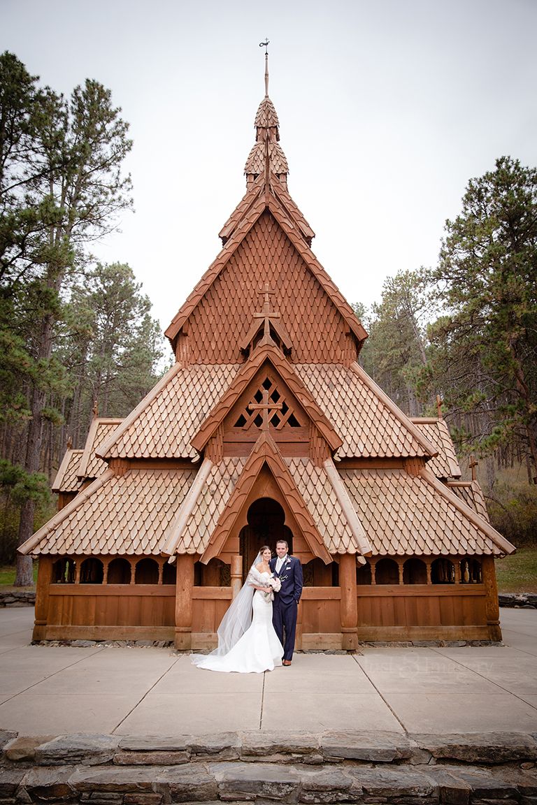 bride and groom standing outside ancient wooden cathedral