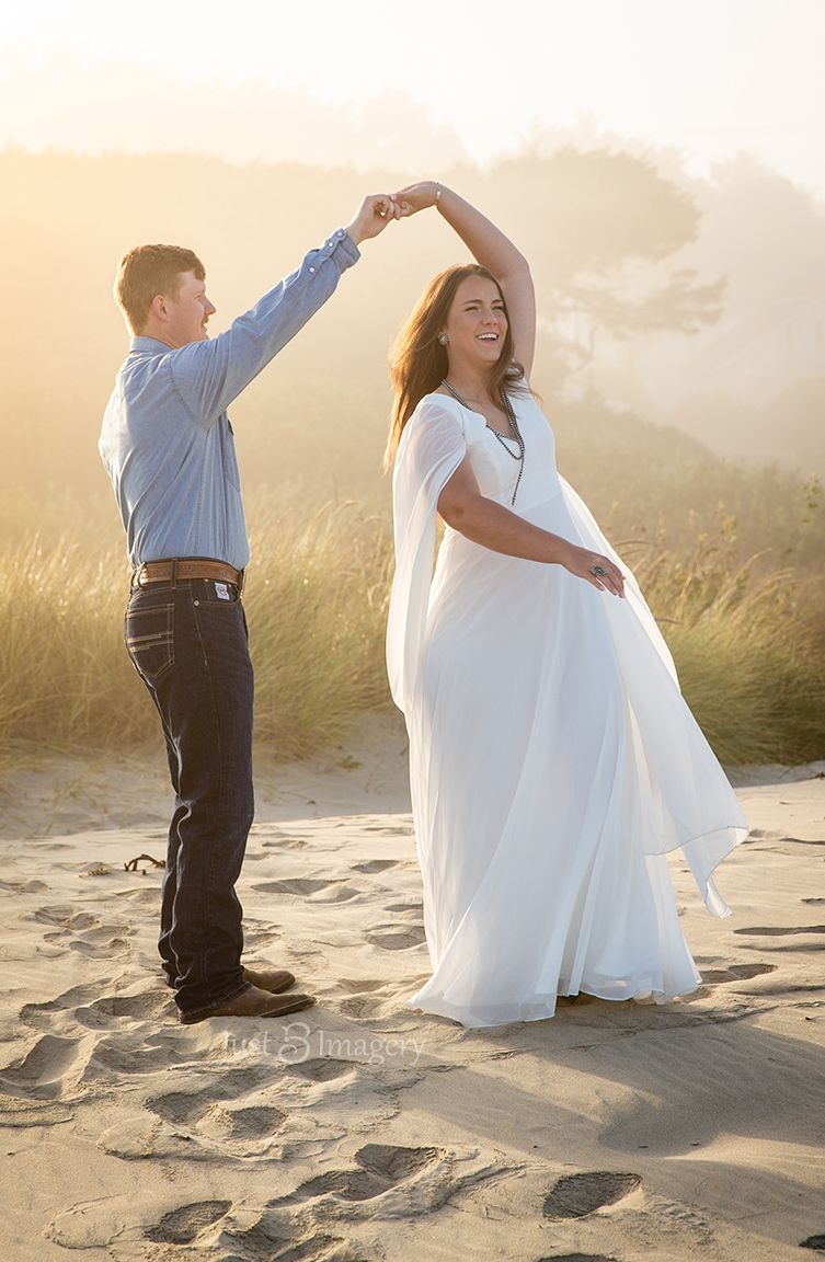engaged couple dancing on the beach in the fog in Oregon
