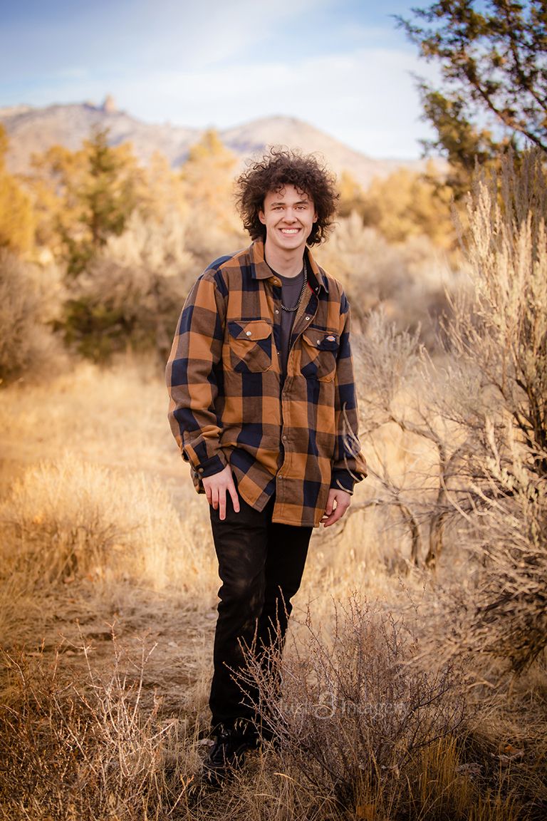 high school senior boy in Central Oregon, near Redmond, standing in high desert landscape with buttes behind him