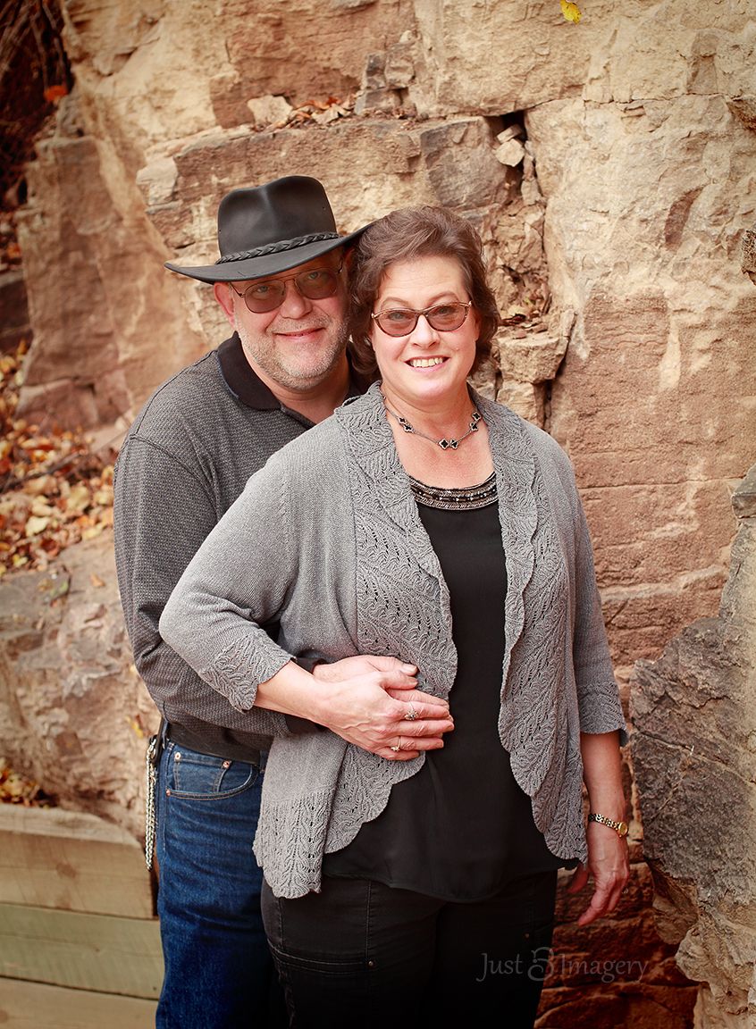 mature engaged couple posing with rock background