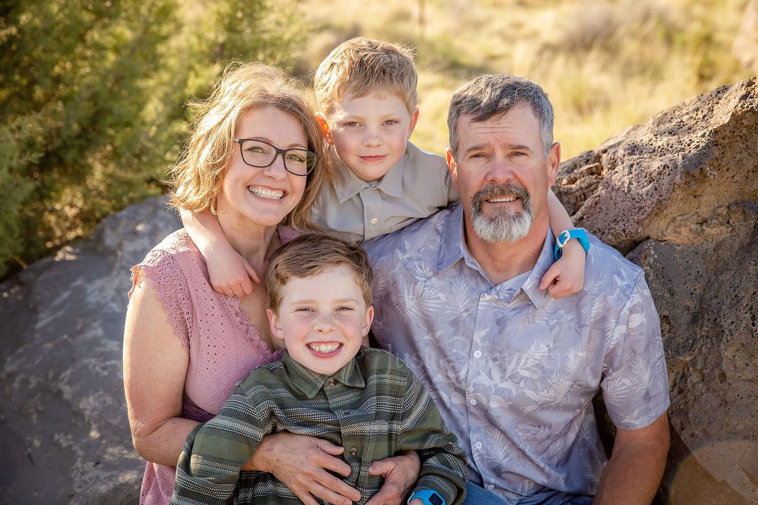 grandma and grandpa with two grandsons sitting in Central Oregon high desert, backlit, and all smiles