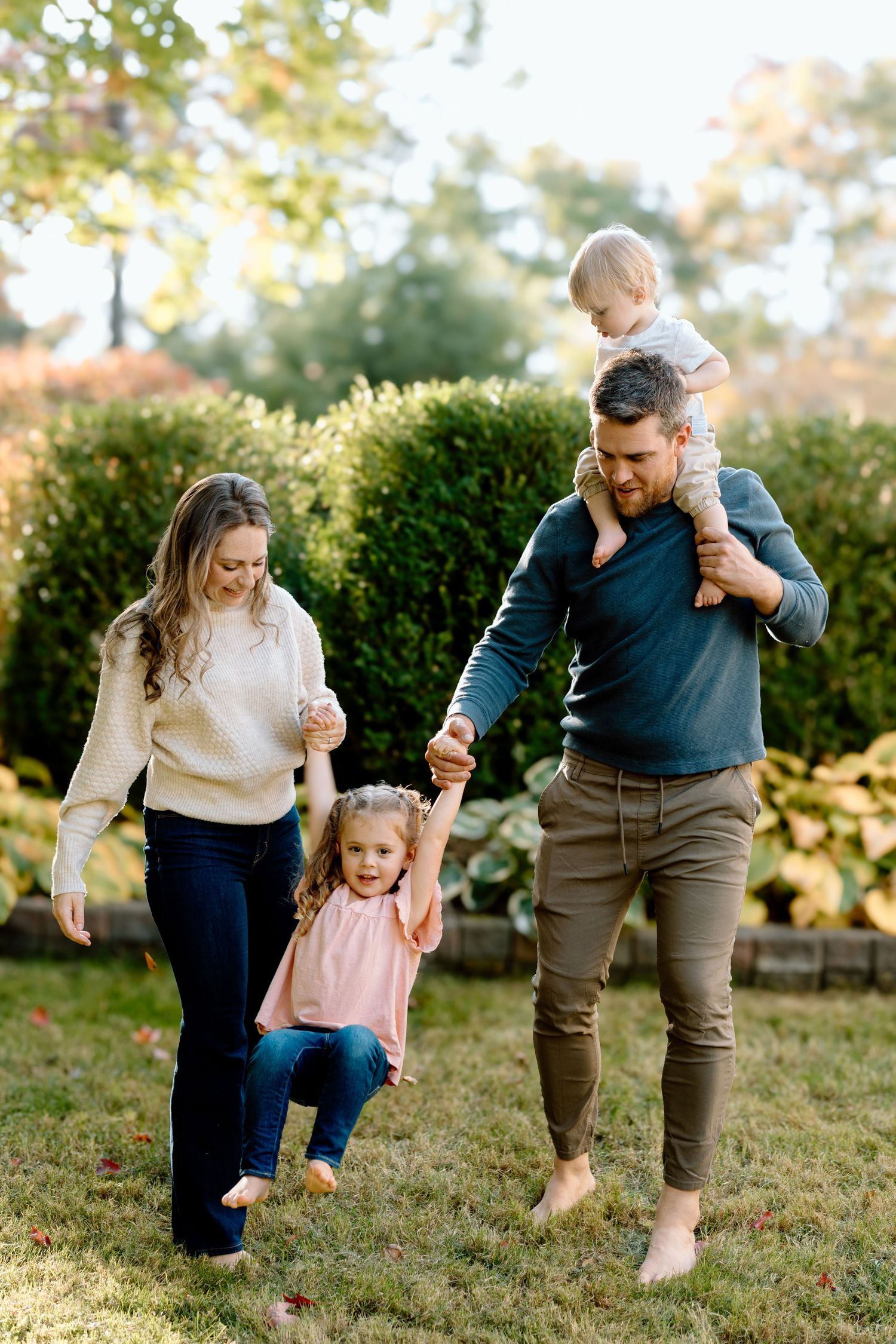 Family playing and running together in a sunlit backyard garden.