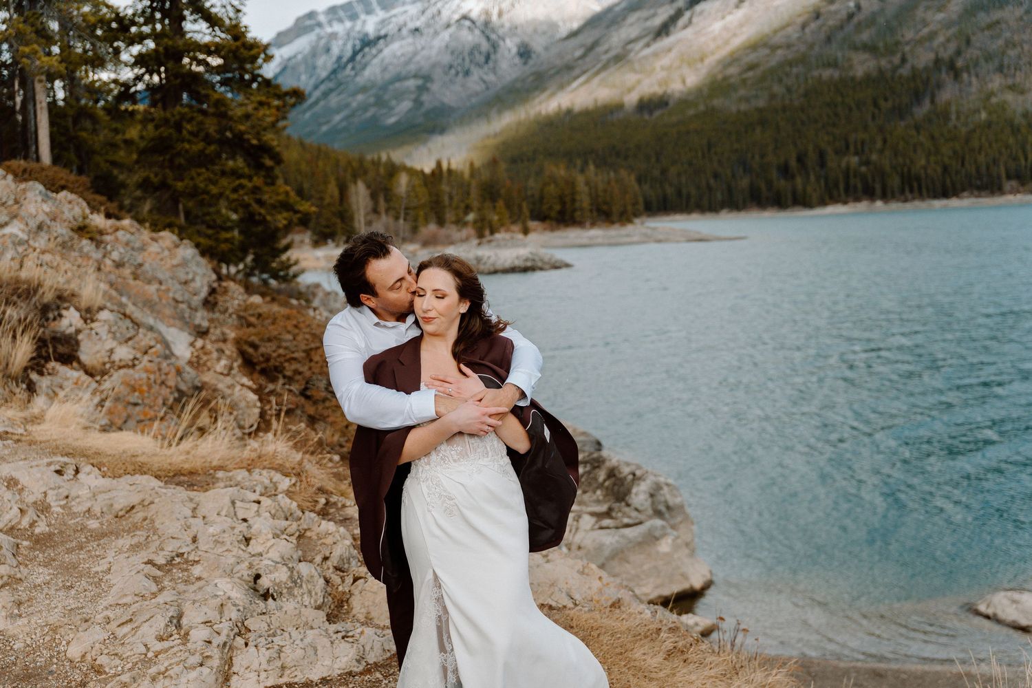 Intimate wedding photos captured against a backdrop of snow-dusted mountains and a serene lake.