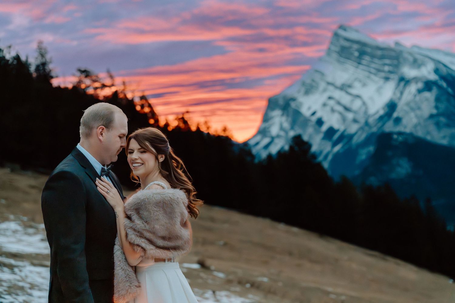 A couple shares an intimate moment at sunset with Mount Rundle in Banff National Park.