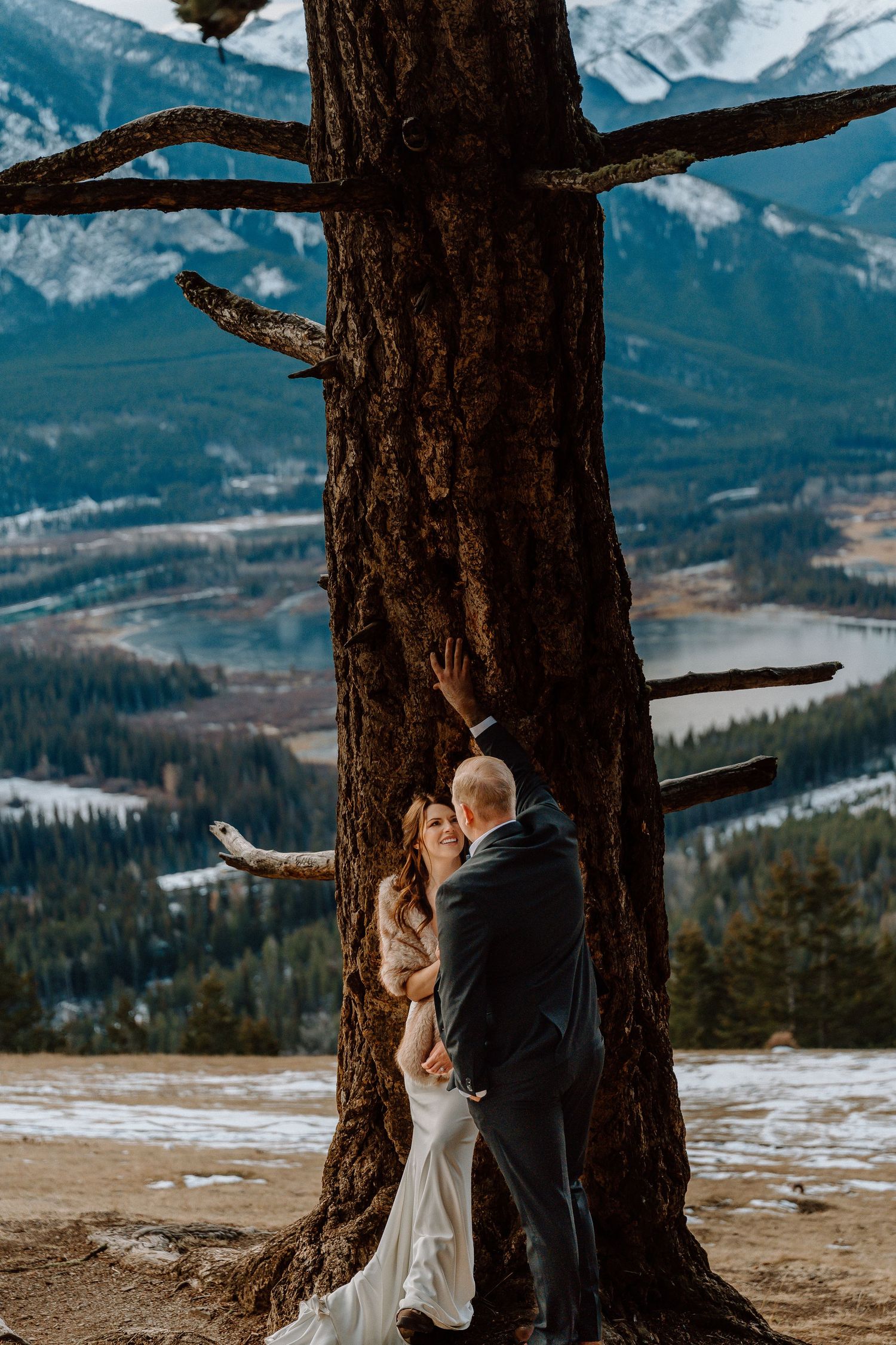 Winter mountain wedding photos with snow-capped peaks and tall pine trees framing the scene.