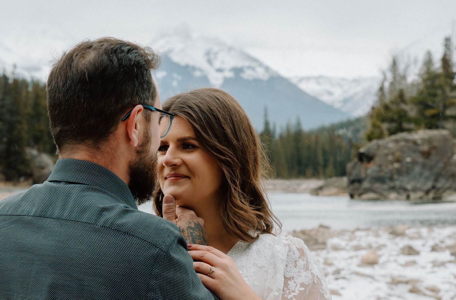 A romantic mountain engagement photo with snow-capped peaks in the background.