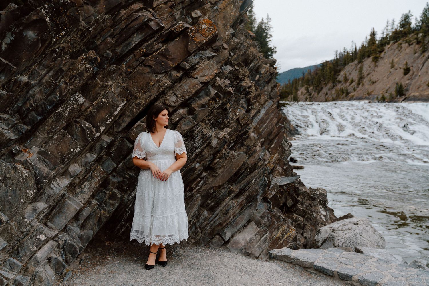 Wedding couple embracing on a rocky mountain shoreline during winter.