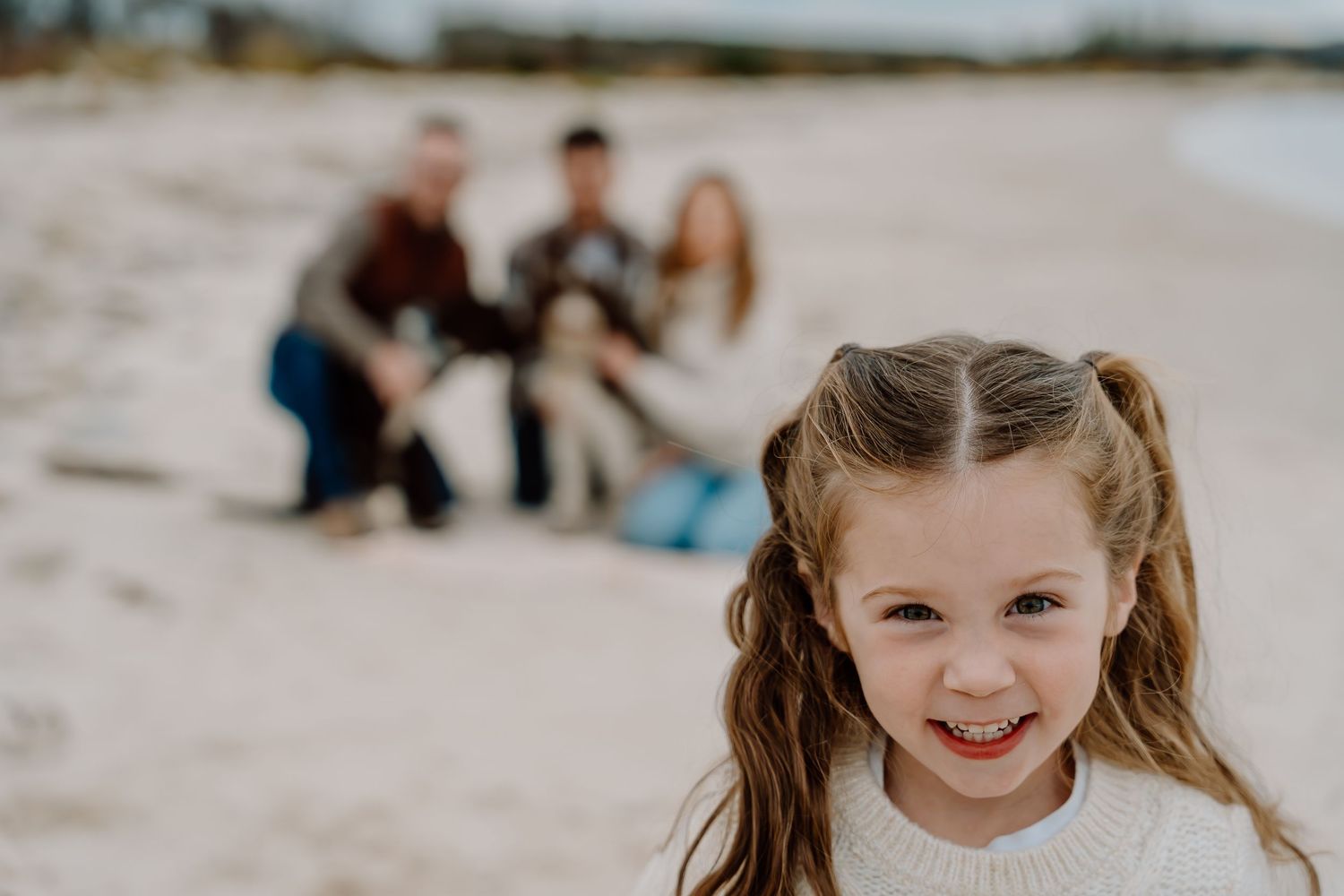 Beachside portrait session with joyful expressions against sandy backdrop.