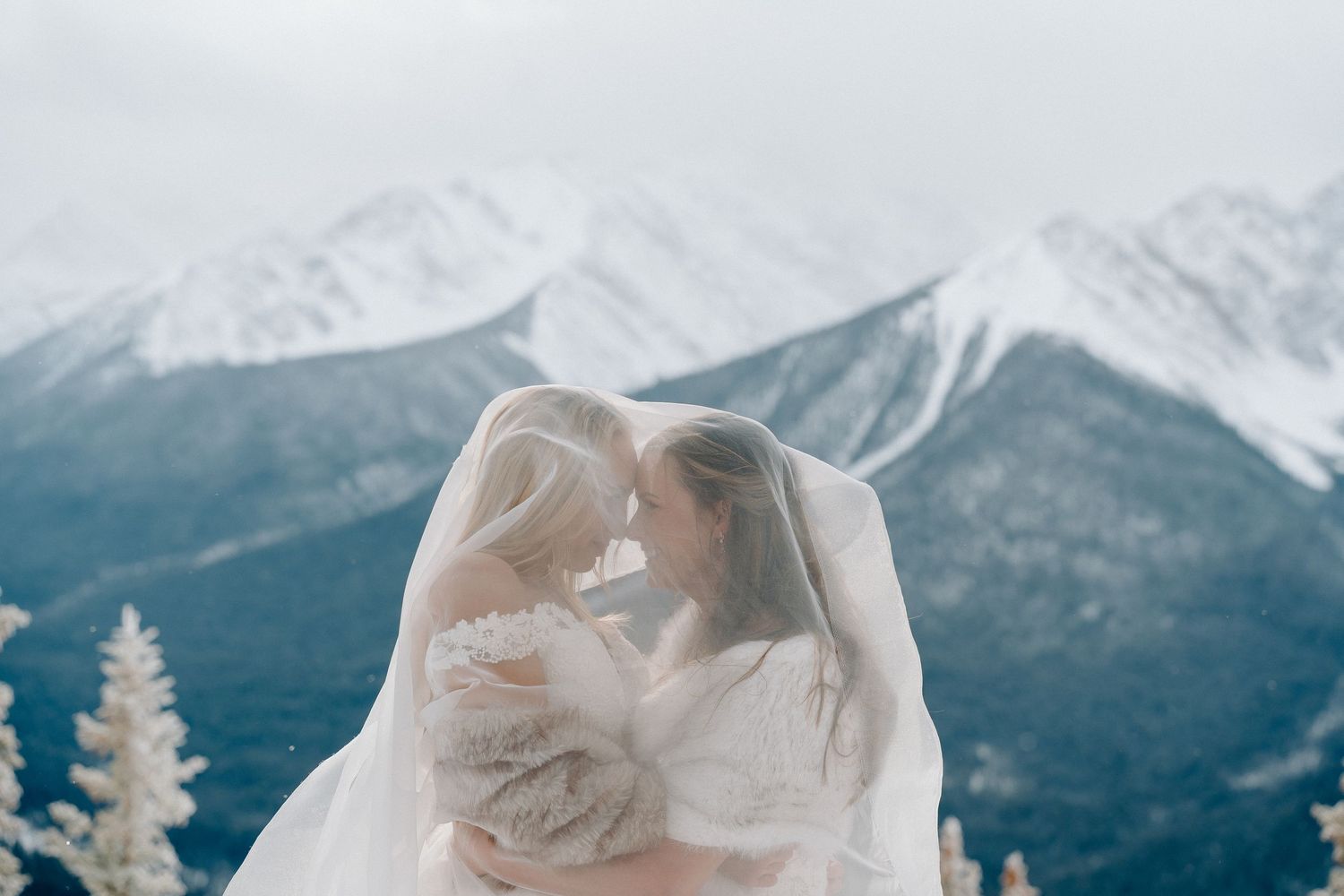 Ethereal white veil flowing in the wind with snow-covered mountain peaks in the background.