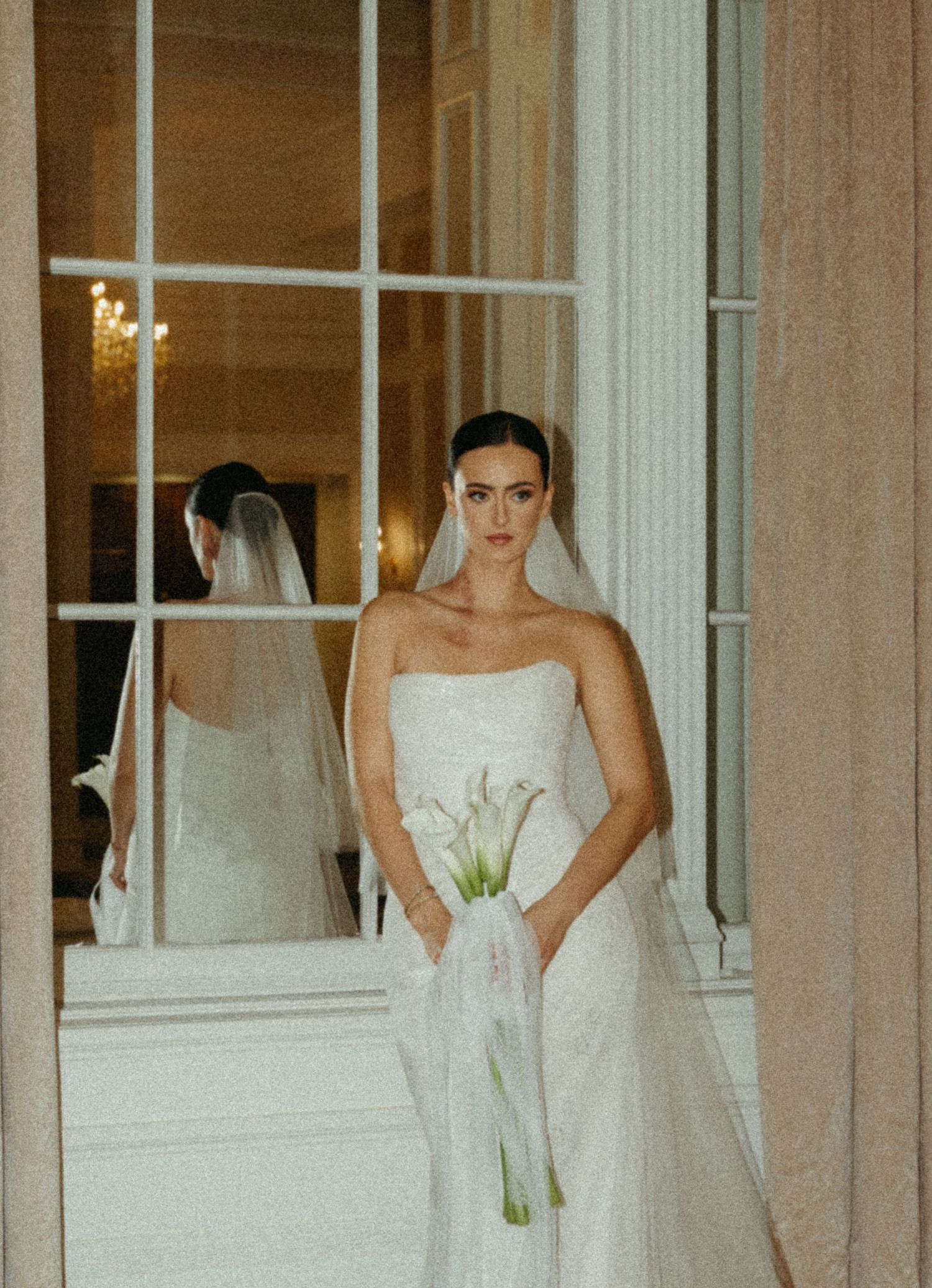 A row of elegant white wedding dresses displayed in a brightly lit boutique window.