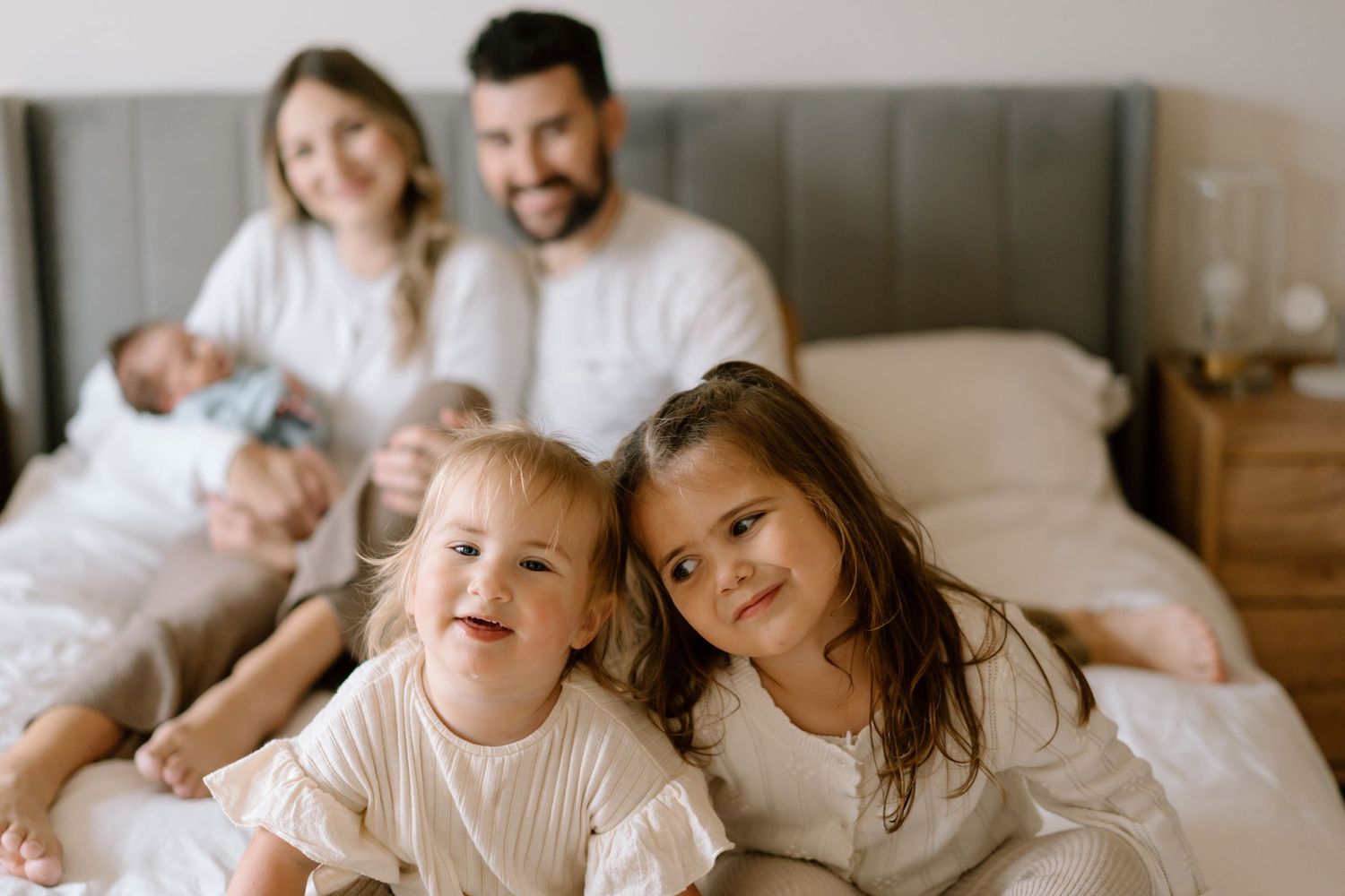 Sweet family bonding moment photographed in warm natural light on a bed.