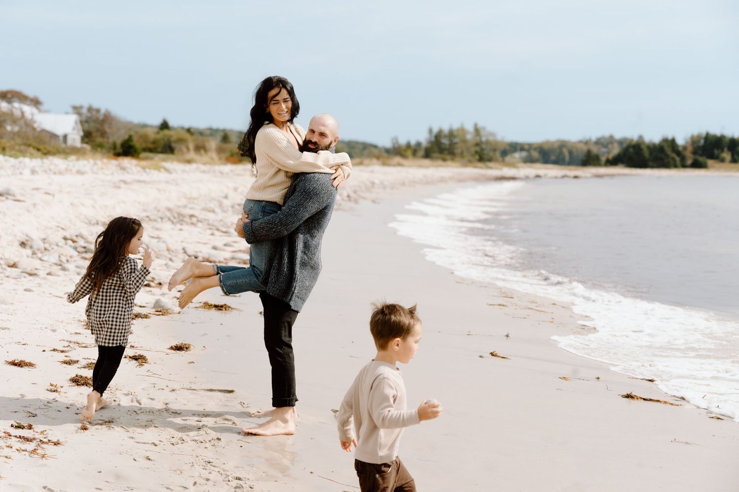 Family walking and playing along a scenic beach shoreline.