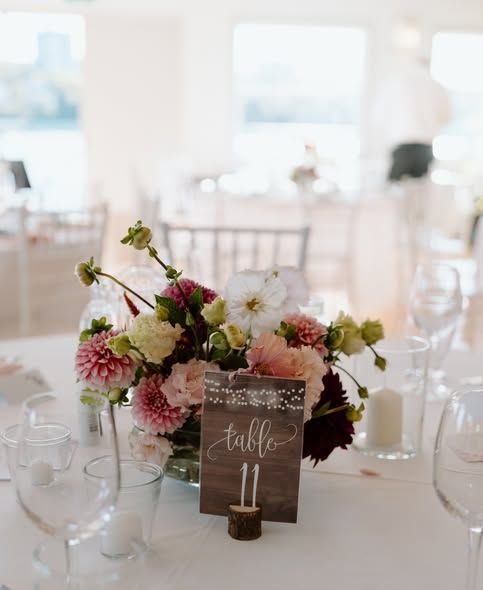 Wedding reception table settings with rustic wooden table numbers and floral centerpieces.