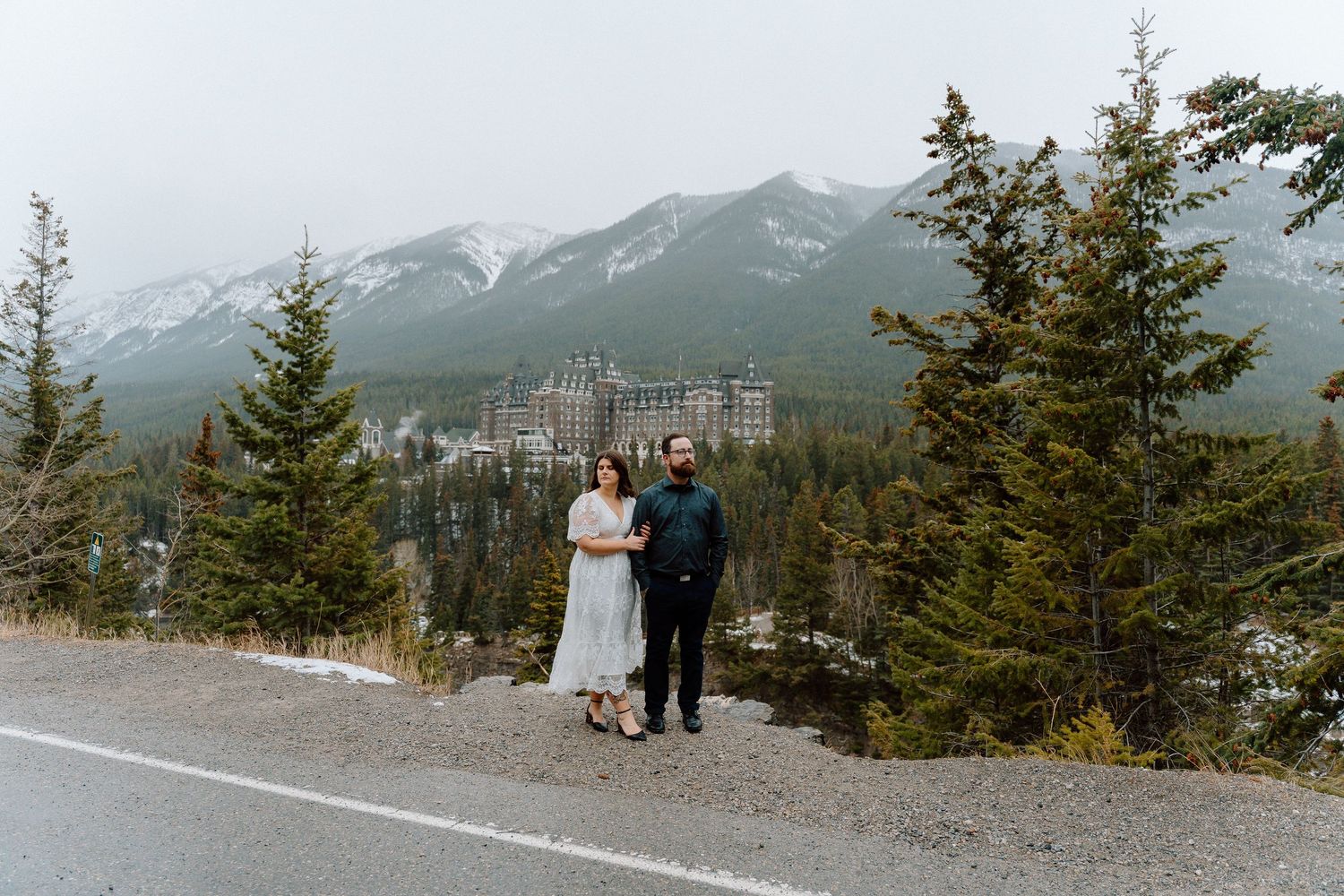 A couple stands on Sulphur Mountain viewing platform overlooking the majestic Canadian Rocky Mountains in Banff National Park.