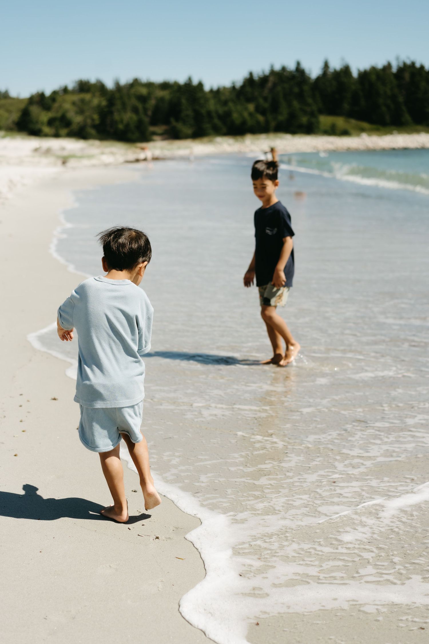 A sequence of photos showing a child playing in the gentle waves along a pristine white sandy beach on a sunny day.