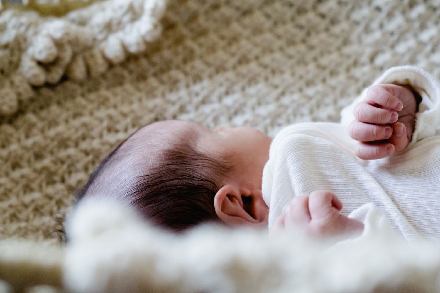 Minimalist newborn photography with soft white fabrics and natural lighting.