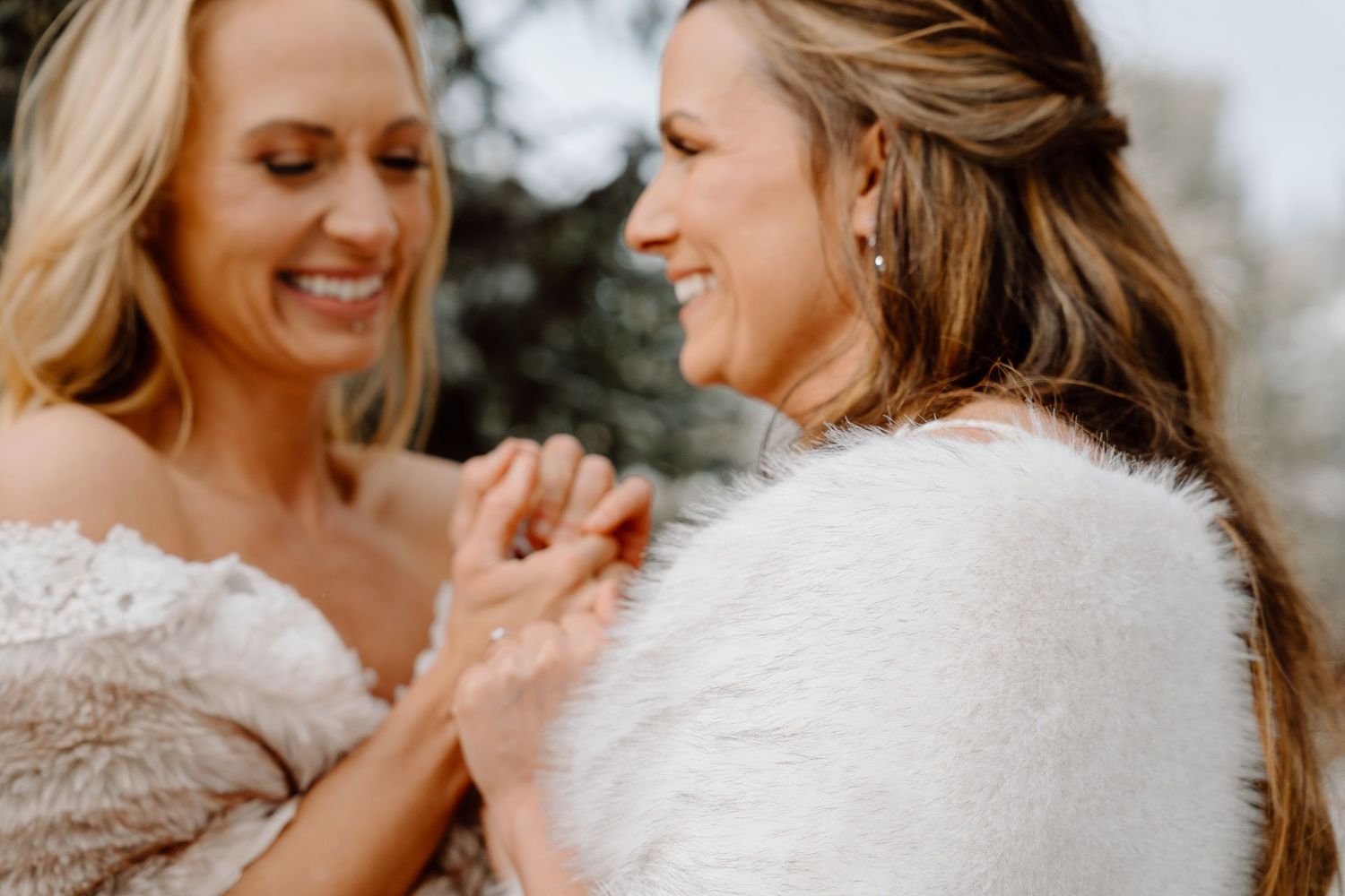 Two people in white dresses share joyful moments together in snowy mountain scene.