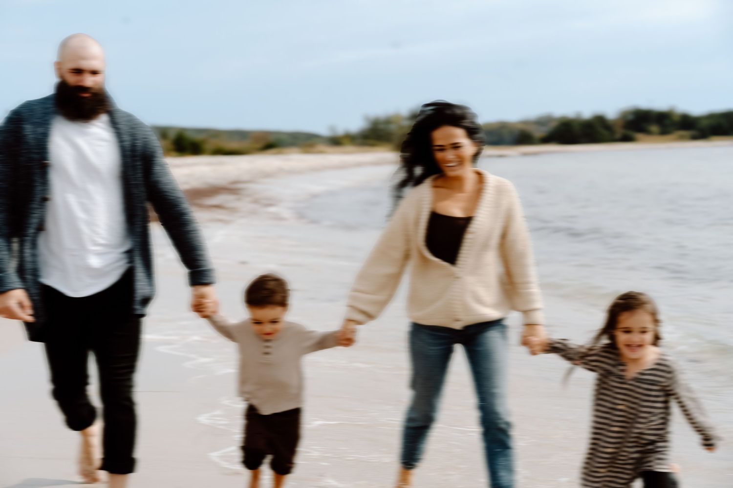 Family walking and playing together on sandy beach.