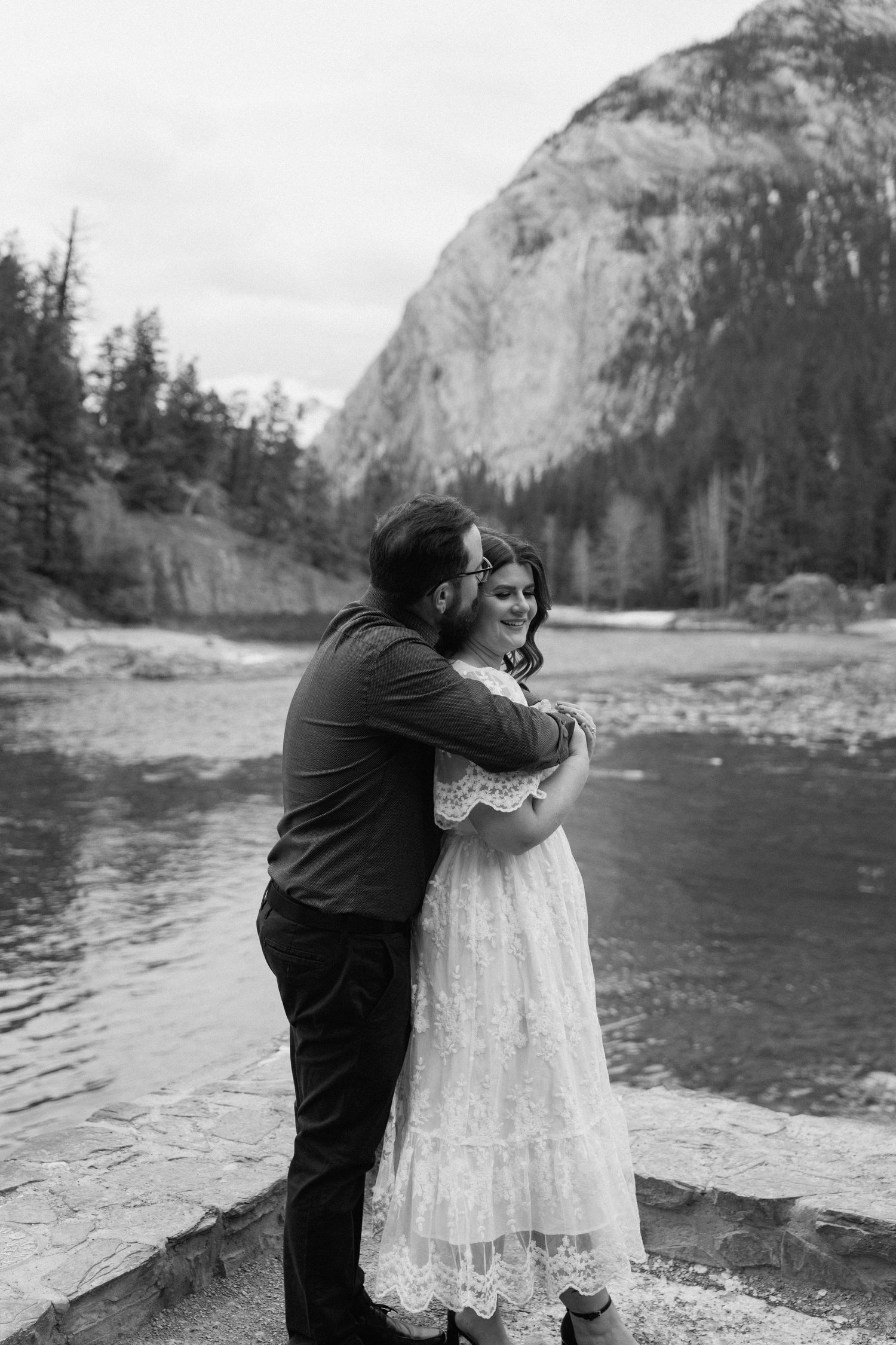 Black and white wedding photos capture tender moments by a scenic mountain lake.