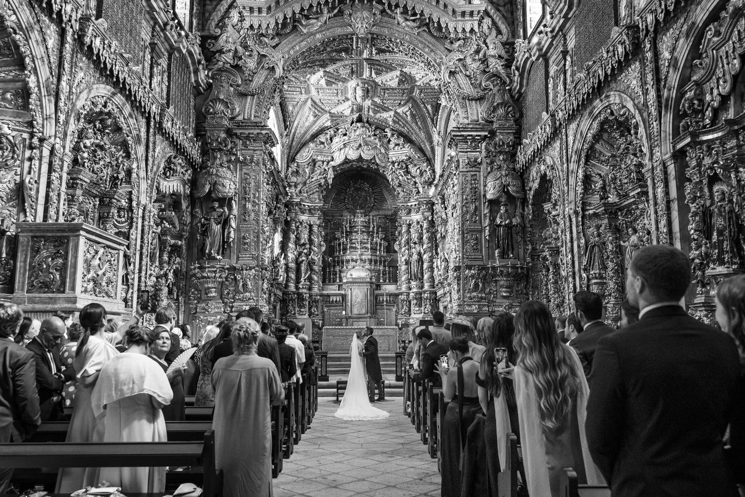 Baroque church interior filled with wedding guests and ornate gold details in black and white.