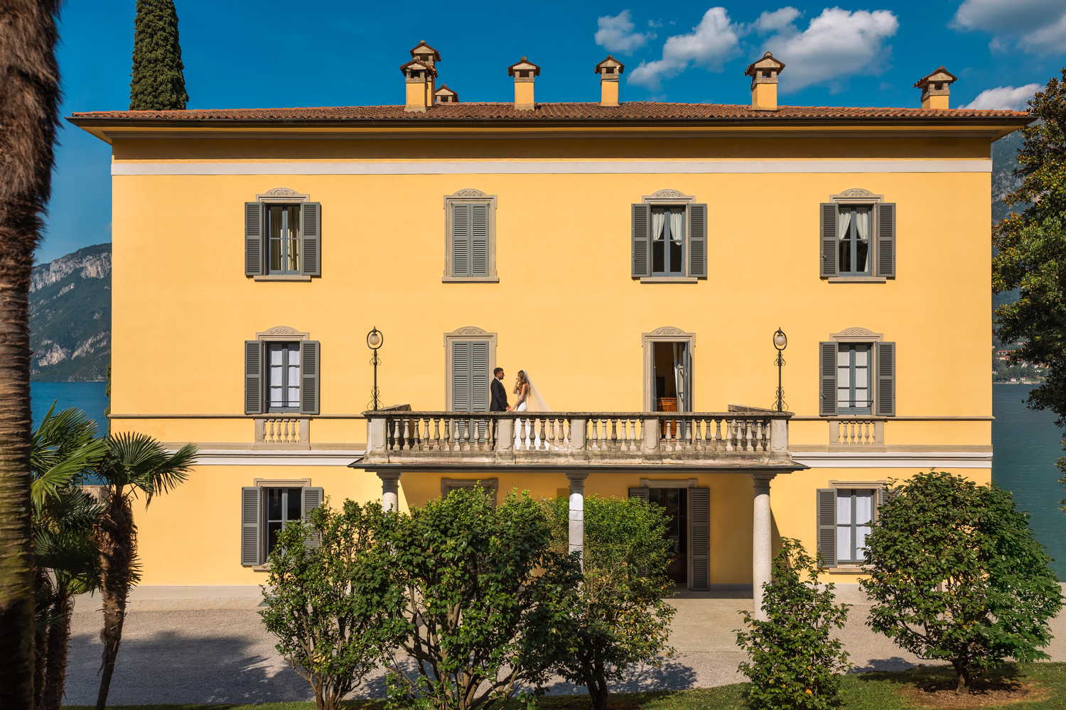 Bride and groom captured in a timeless portrait outside a yellow villa in Lake Como.