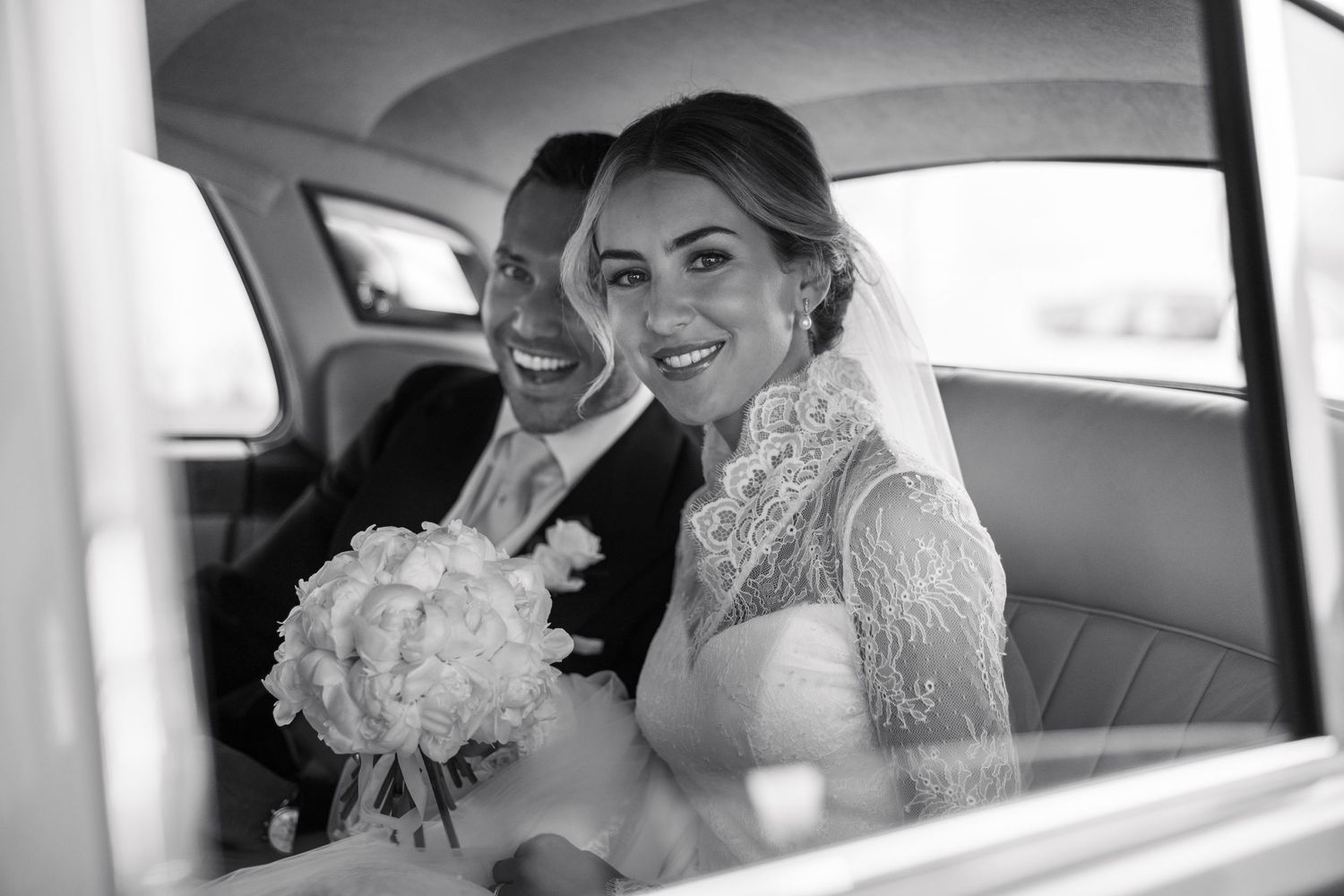Wedding couple shares a joyful moment inside a classic car.