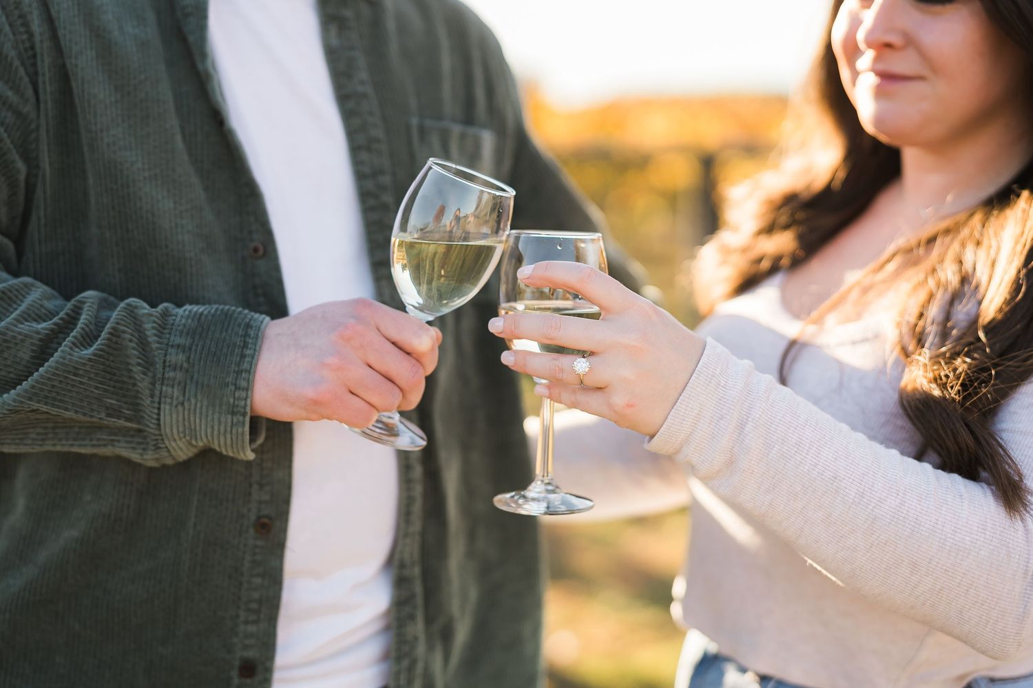 Two people toasting with wine glasses at sunset in an outdoor setting.