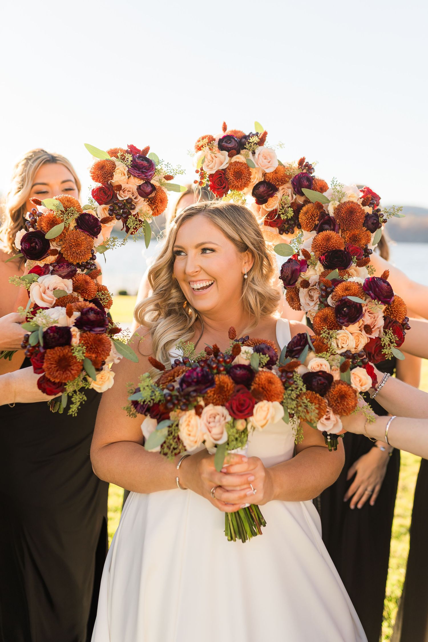 Beautiful fall-colored wedding bouquets featuring burgundy, orange and pink flowers in rich autumn tones.