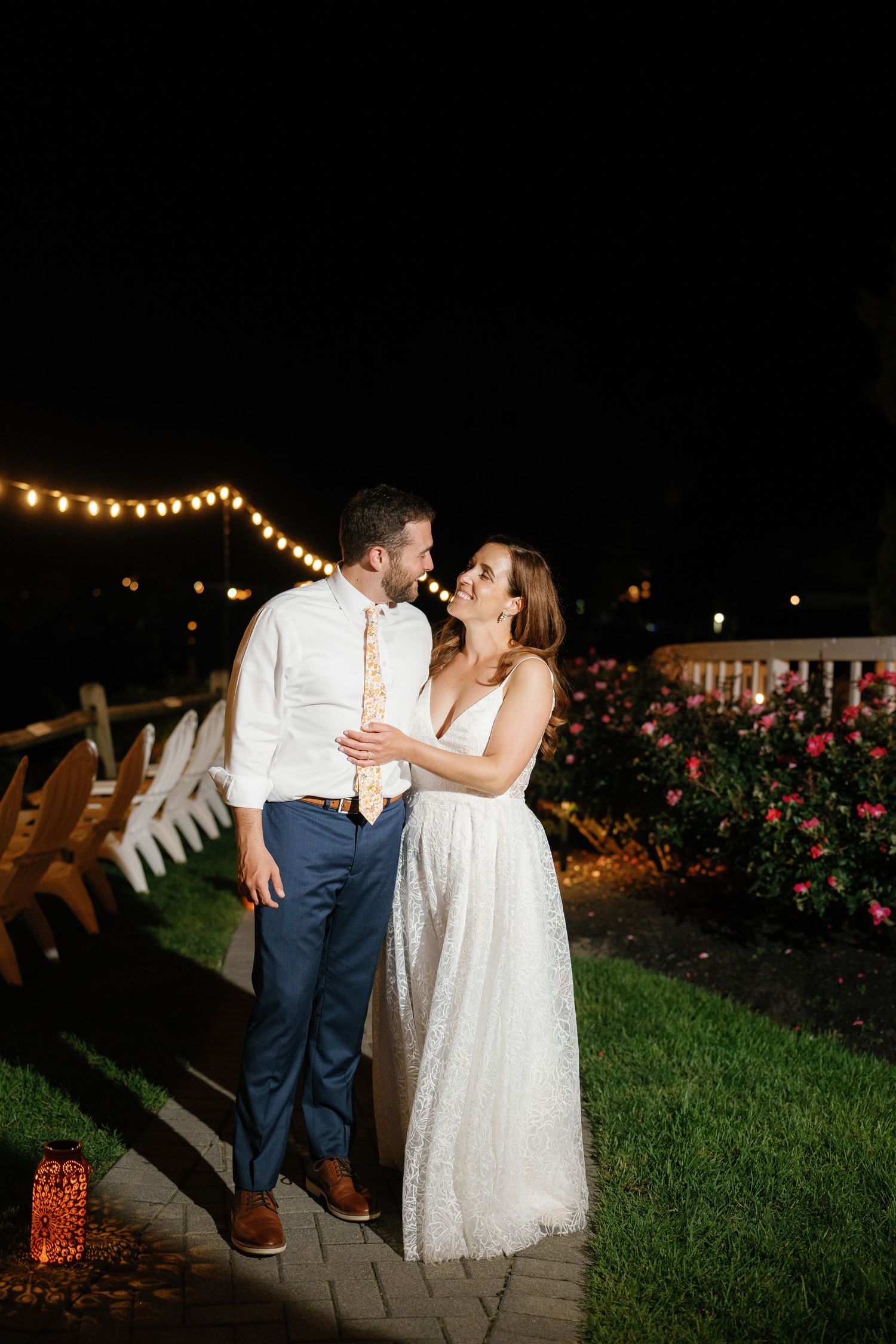 A romantic couple shares an intimate dance moment under twinkling lights in a garden at night.