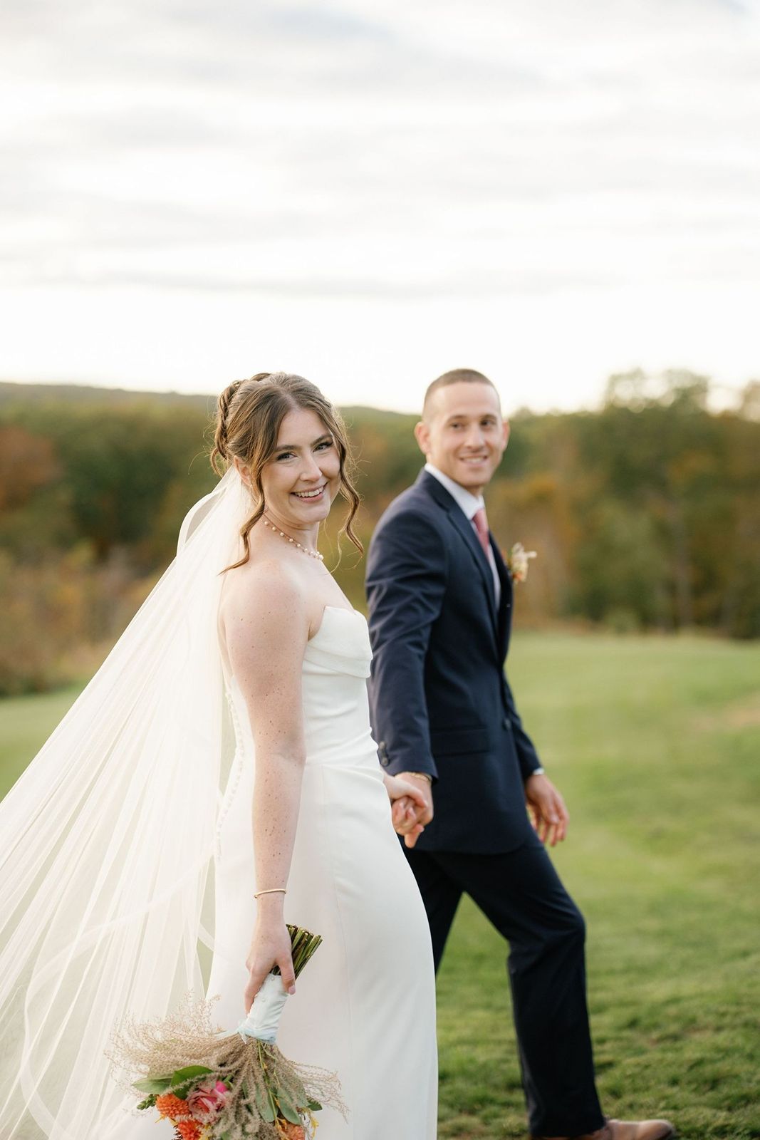 Groom looks at bride smiling at camera during Long Island wedding photography session