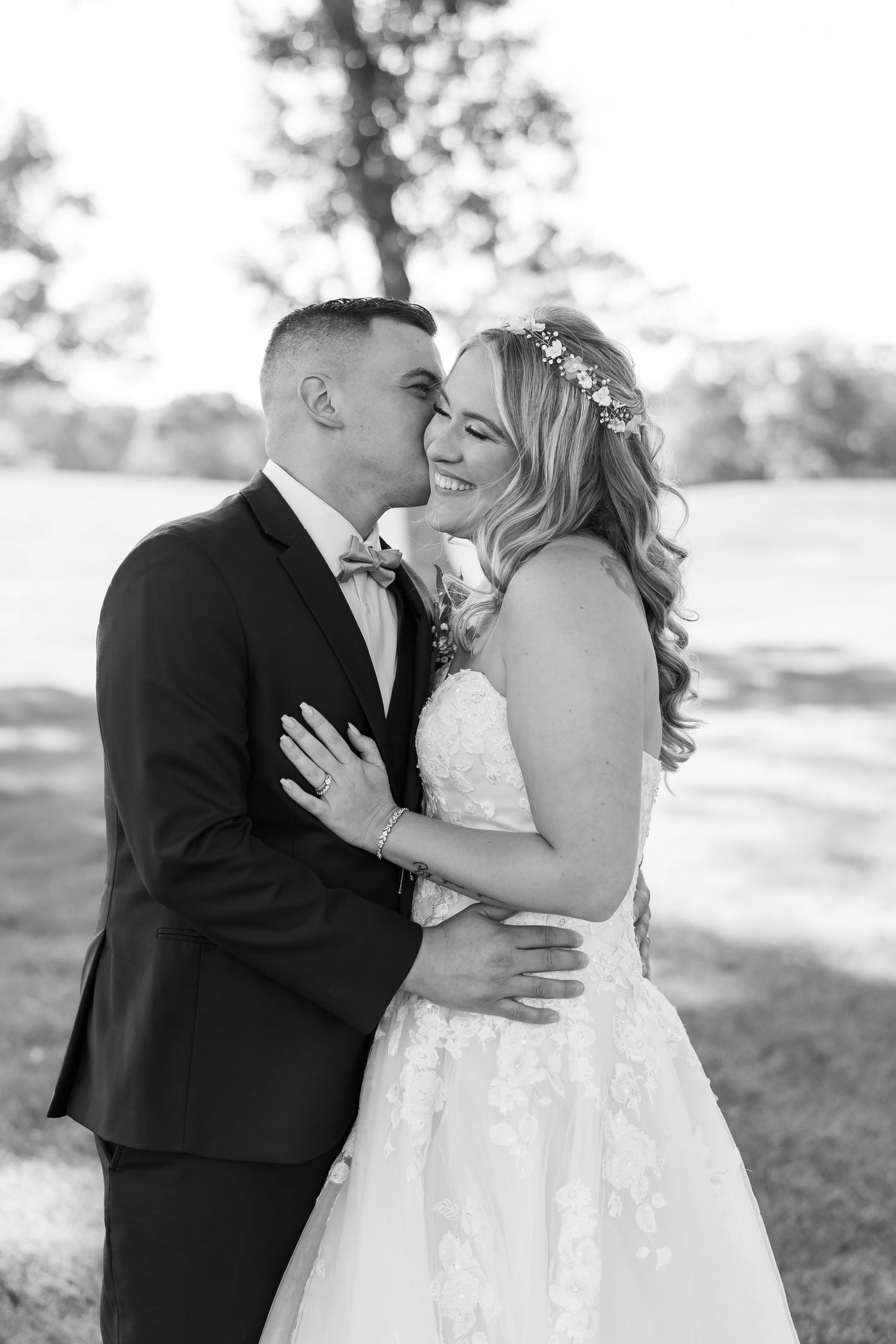A romantic black and white photo series of a couple sharing tender moments in their wedding attire outdoors.