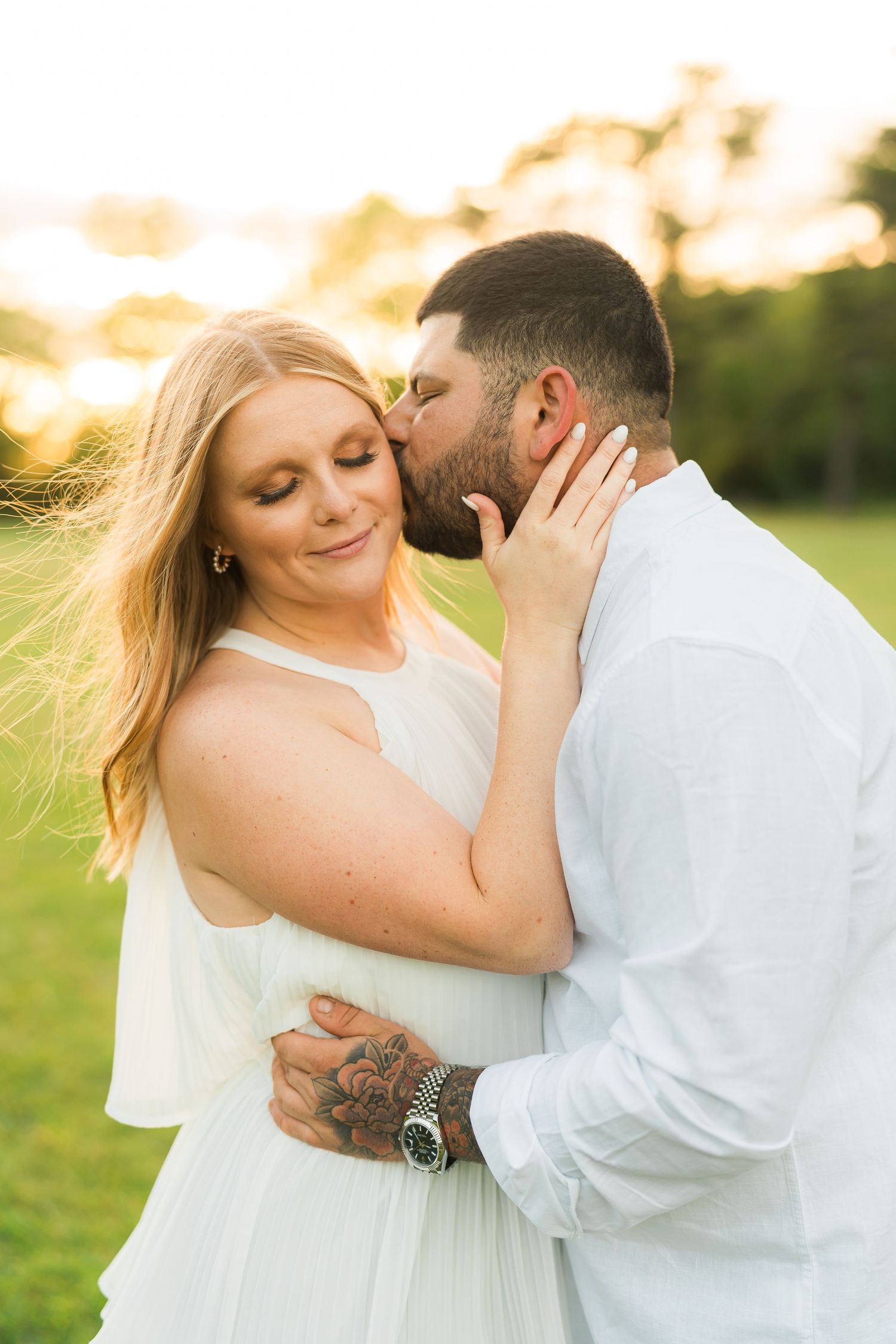 Romantic sunset engagement portrait in white outfits with golden lighting.