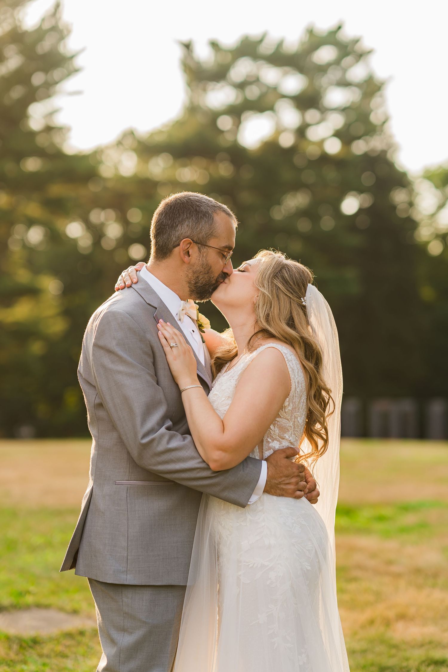 A romantic wedding moment captured at sunset with the couple embracing.