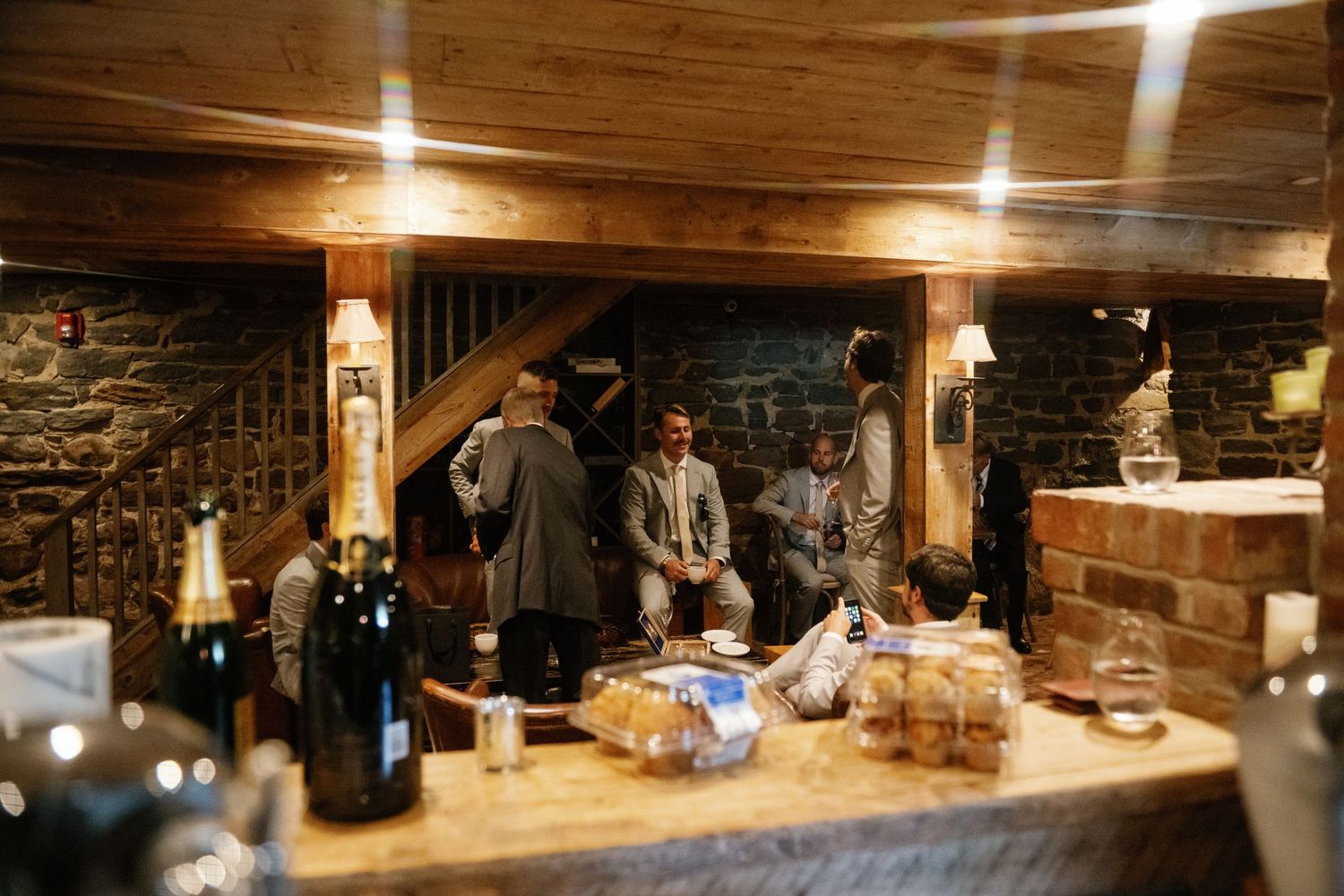 A rustic stone-walled basement room with wooden beams and warm lighting creates a cozy gathering space.