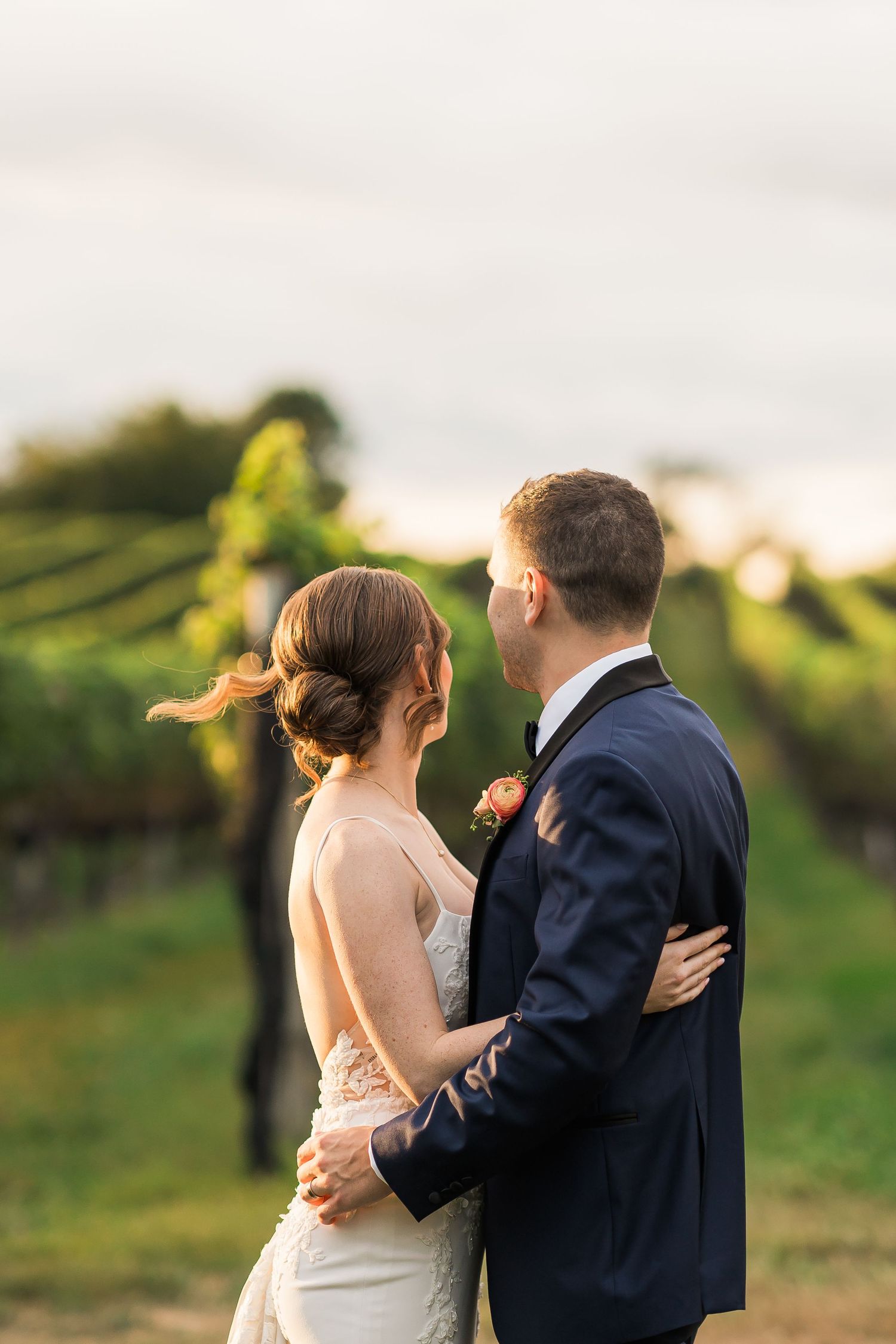 Newlywed couple embraces in golden sunset light during outdoor wedding photoshoot.