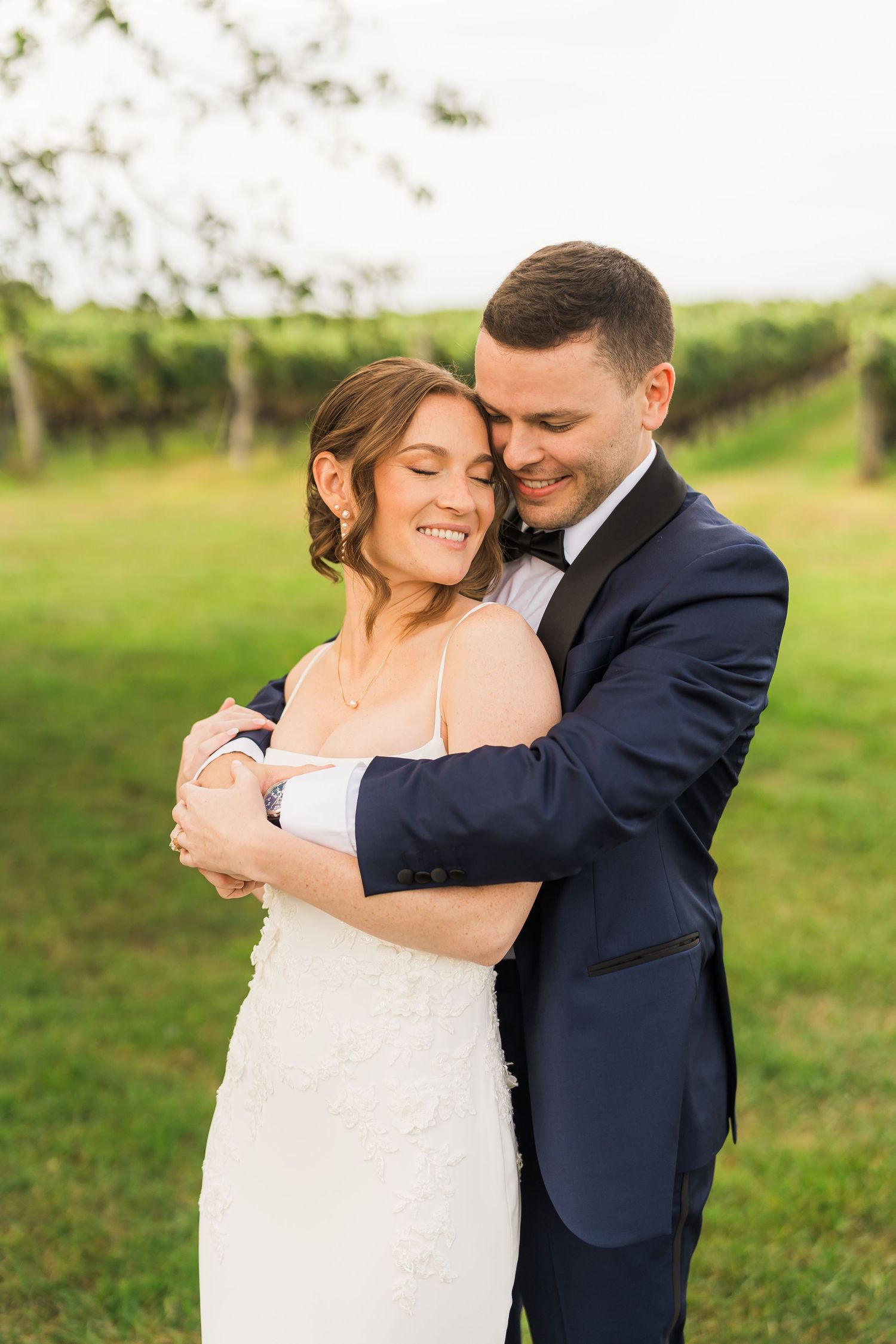 A tender embrace between newlyweds in a sunny vineyard setting during their wedding celebration.
